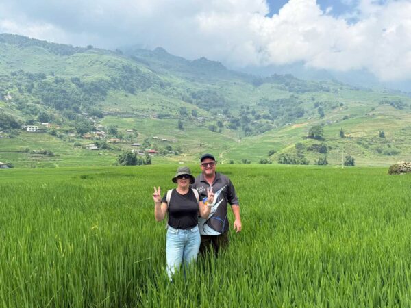 two tourist trekking trhough lush green rice field